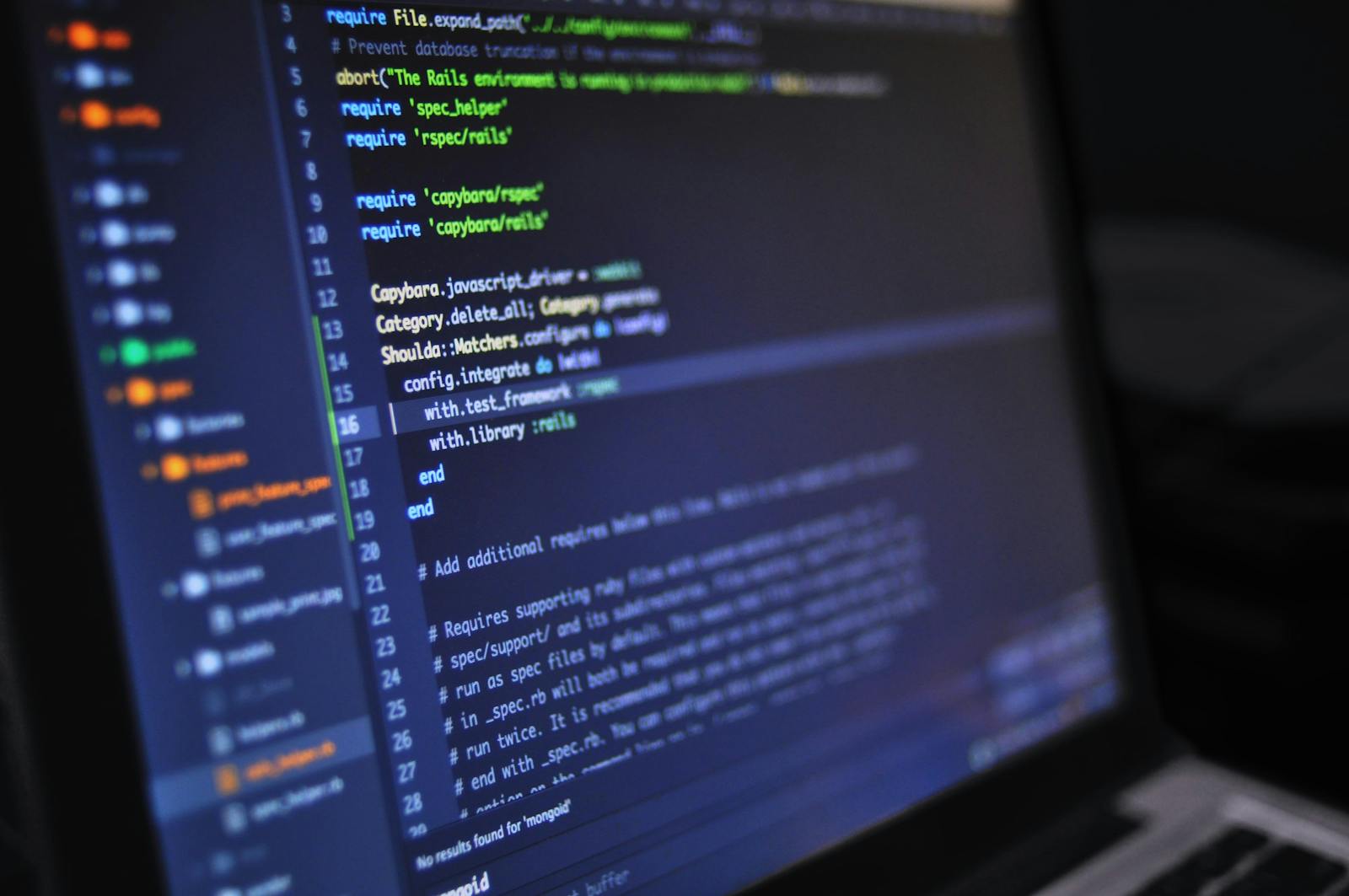 Close-up of a computer screen displaying programming code in a dark environment