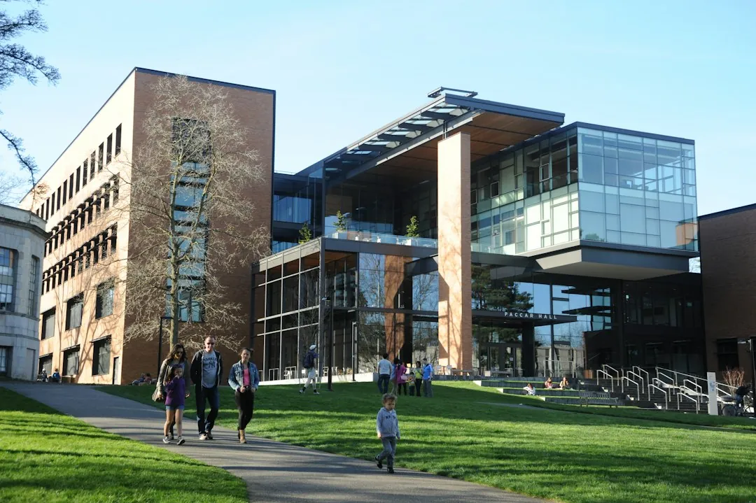 Studierende gehen auf dem Campus vor einem modernen Hochschulgebäude